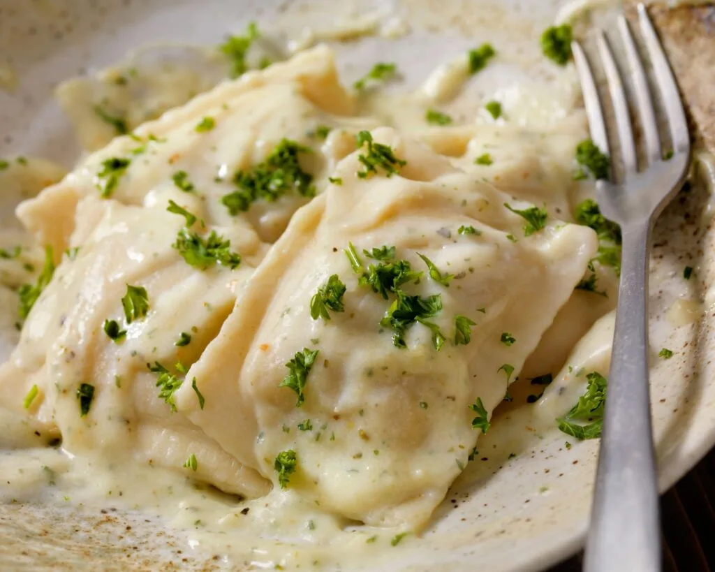 Cozy Cajun Alfredo Sauce Without Heavy Cream in 15 Minutes 3 Plate of creamy Cajun Alfredo sauce without heavy cream served over fettuccine pasta, garnished with chopped parsley and red pepper flakes, in a white bowl on a rustic wooden table