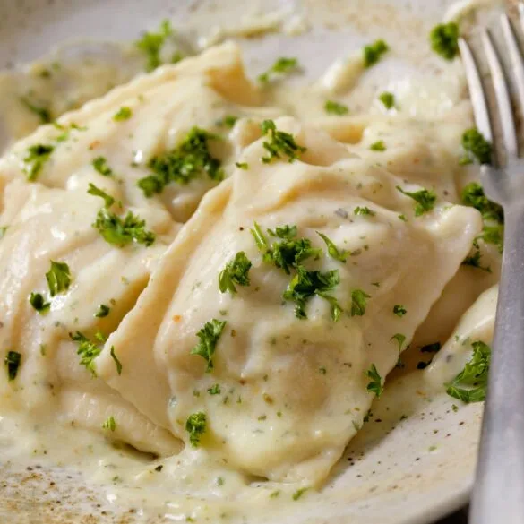 Cozy Cajun Alfredo Sauce Without Heavy Cream in 15 Minutes 5 Plate of creamy Cajun Alfredo sauce without heavy cream served over fettuccine pasta, garnished with chopped parsley and red pepper flakes, in a white bowl on a rustic wooden table
